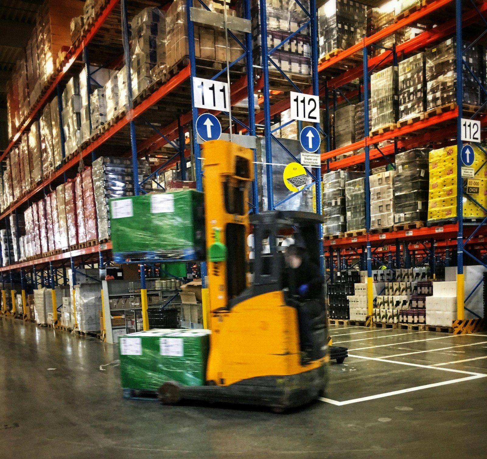 Forklift moving palletized goods through an organized warehouse